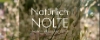 Ein Feld mit blühenden Blumen, im Hintergrund Bäume und blauer Himmel, im Vordergrund die Aufschrift "Natürlich Nolte".