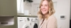 Une femme dans une buanderie moderne avec lave-linge et sèche-linge de Nolte Utility Rooms.