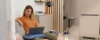 A woman sits on a sofa with a laptop in a modern living room. Nolte Living.