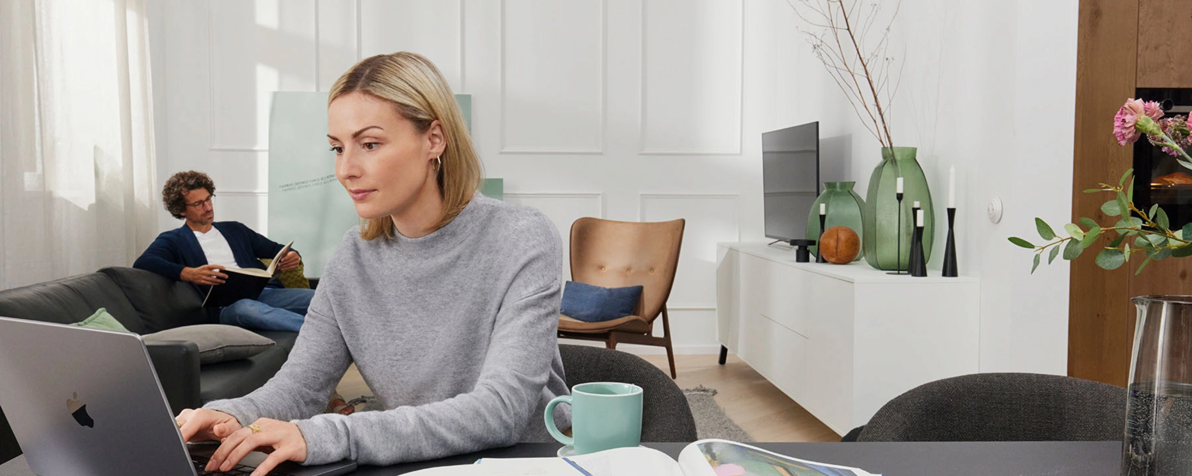 Deux personnes travaillent dans un salon moderne avec des meubles Nolte Living.