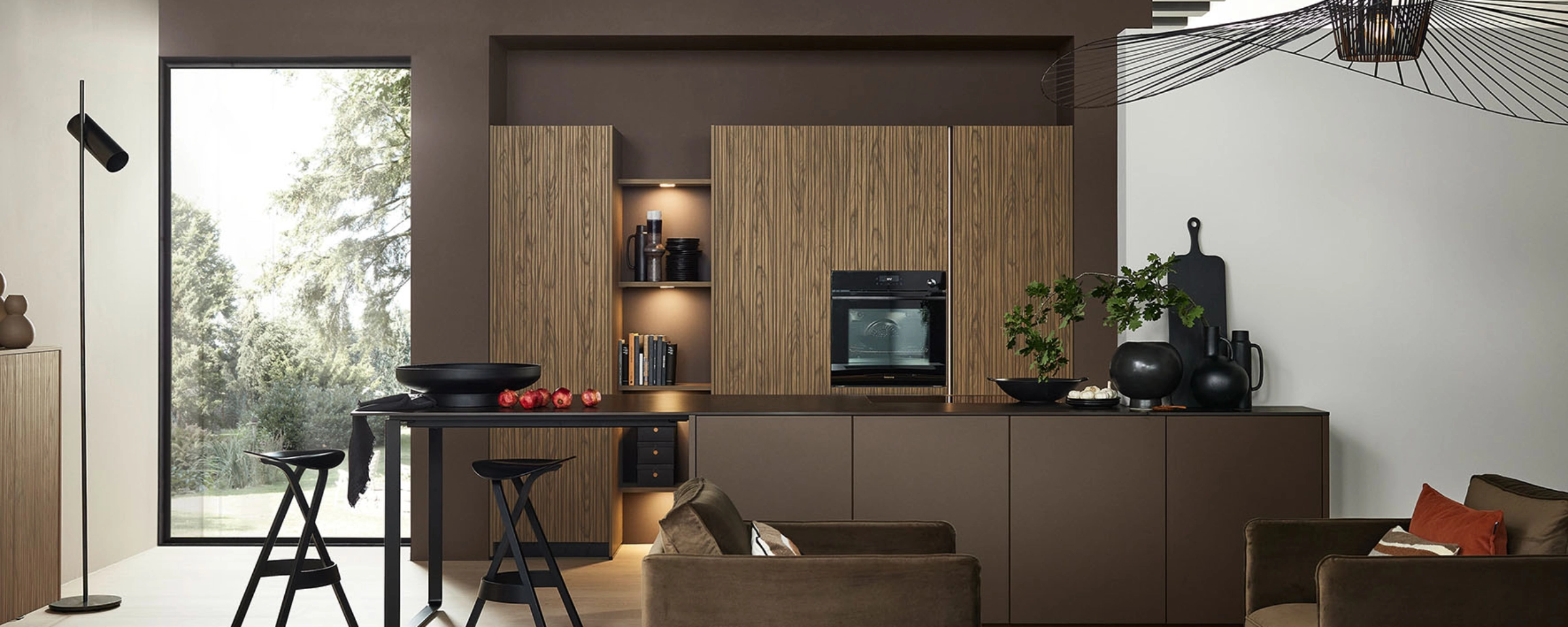 Moderne Küche mit Holzelementen und Essbereich, im Hintergrund große Fenster und stilvolle Dekoration. Nolte Küchen.