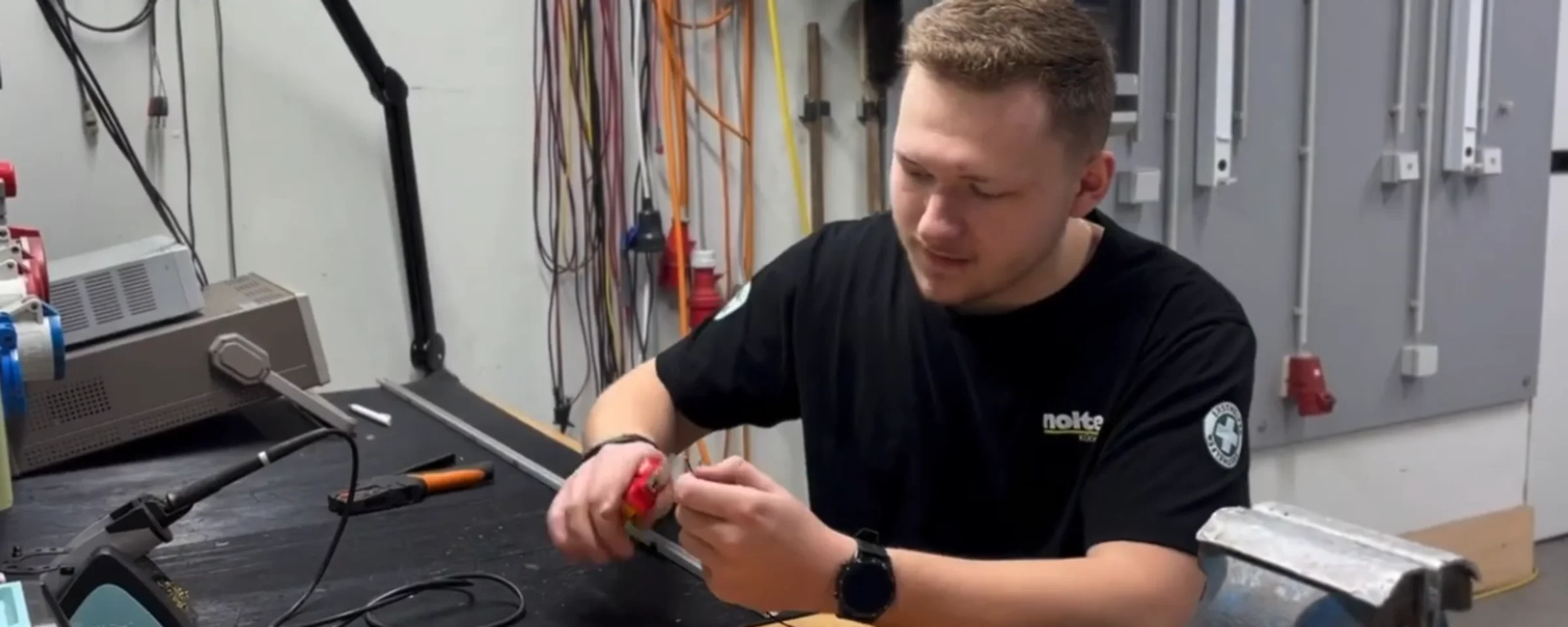 Ein Mann arbeitet in einer Werkstatt mit elektronischen Geräten, Nolte Küchen.