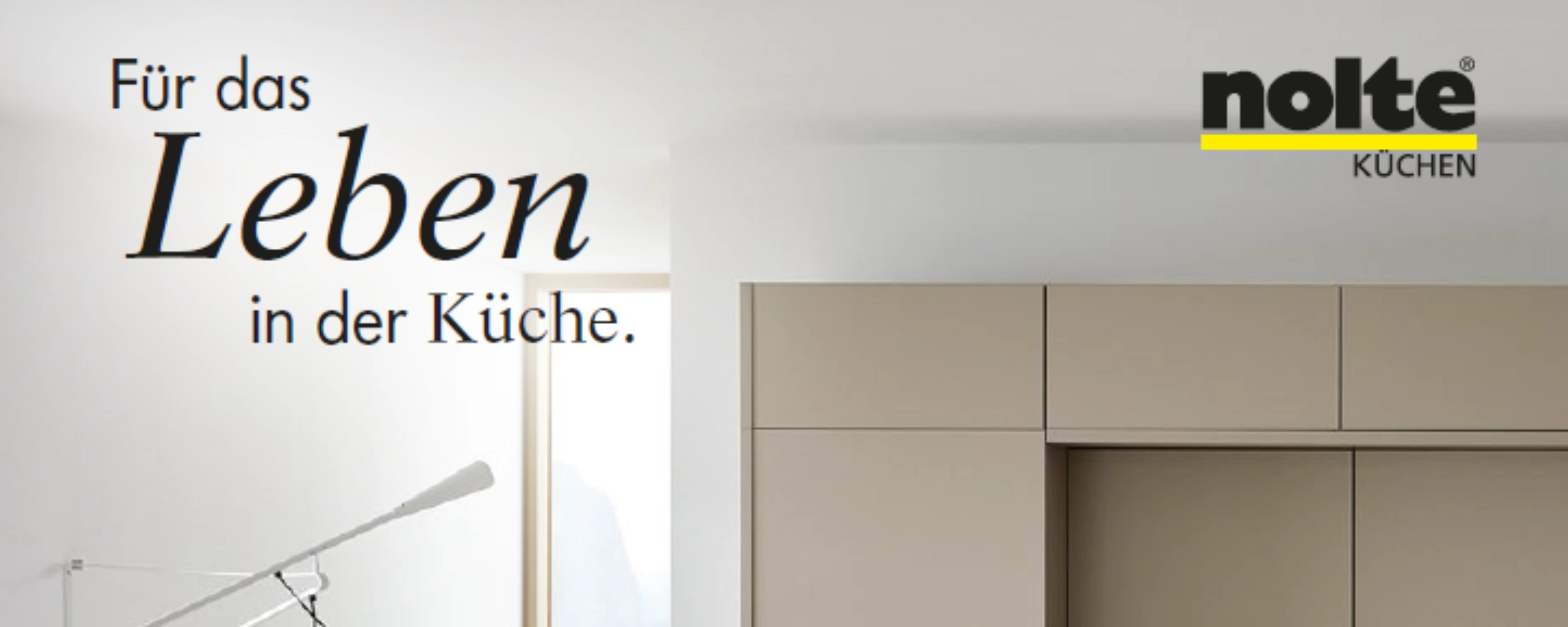 Une cuisine moderne avec des armoires claires et une grande fenêtre, élégamment présentée par Nolte Kitchen.