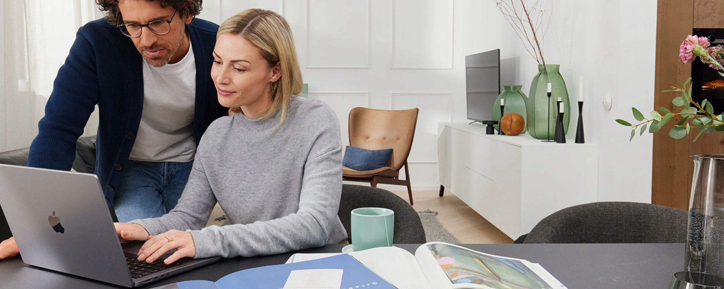 Un couple travaille ensemble sur un ordinateur portable dans un salon moderne avec Nolte Living.