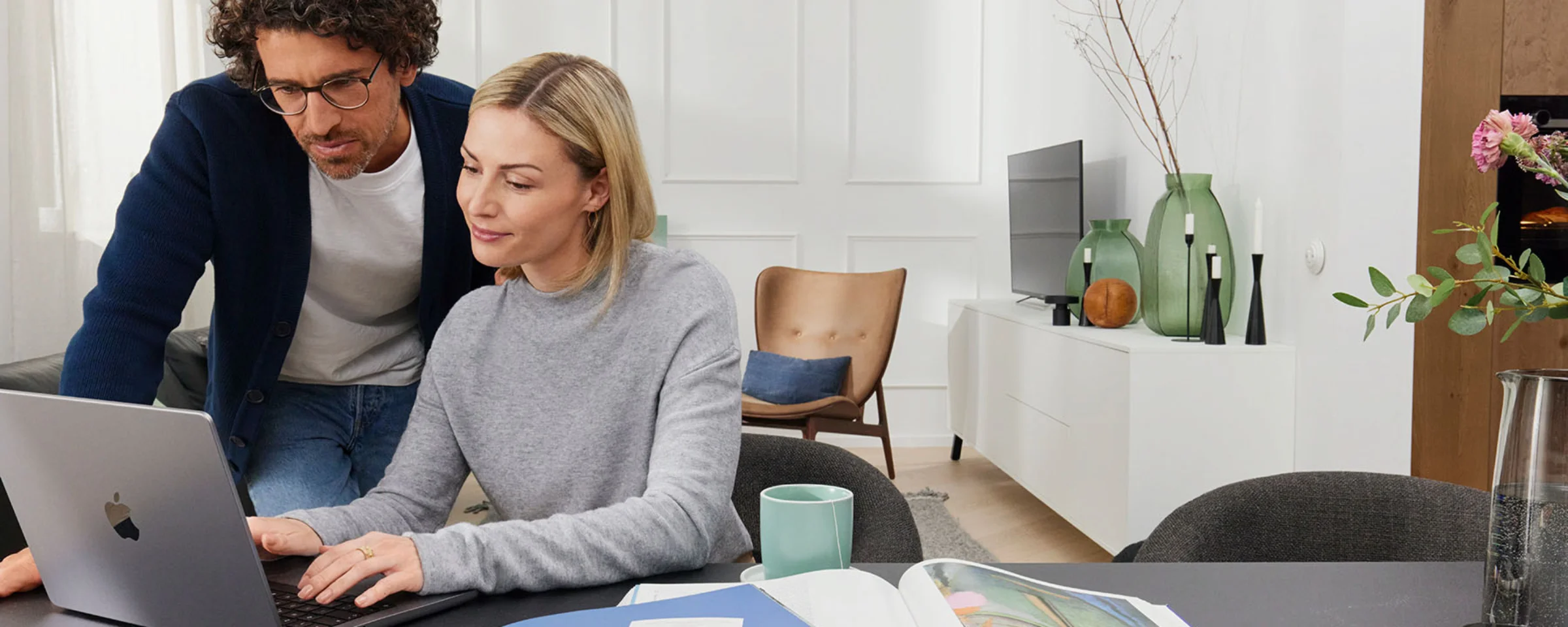 Ein Paar arbeitet an einem Laptop in einem modern eingerichteten Wohnzimmer. Nolte Living.