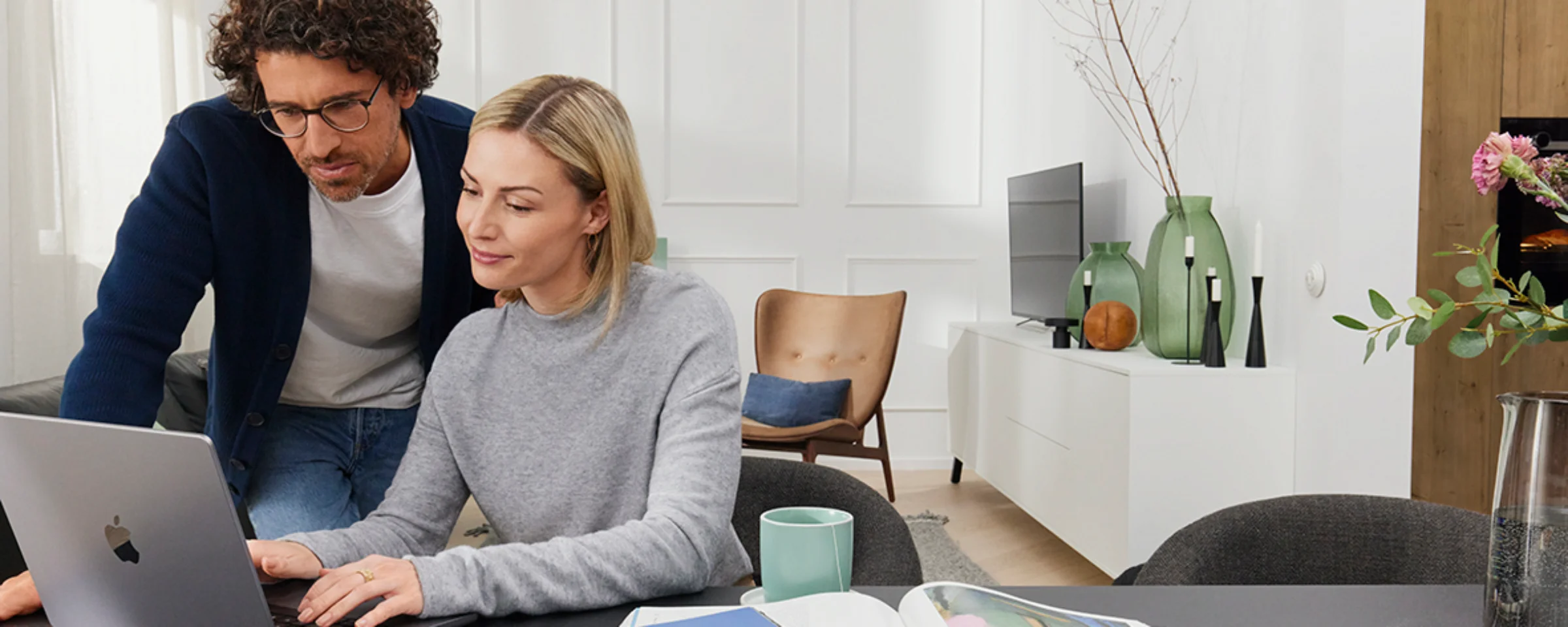 Ein Paar arbeitet an einem Laptop in einem modernen Wohnzimmer mit Nolte Living.