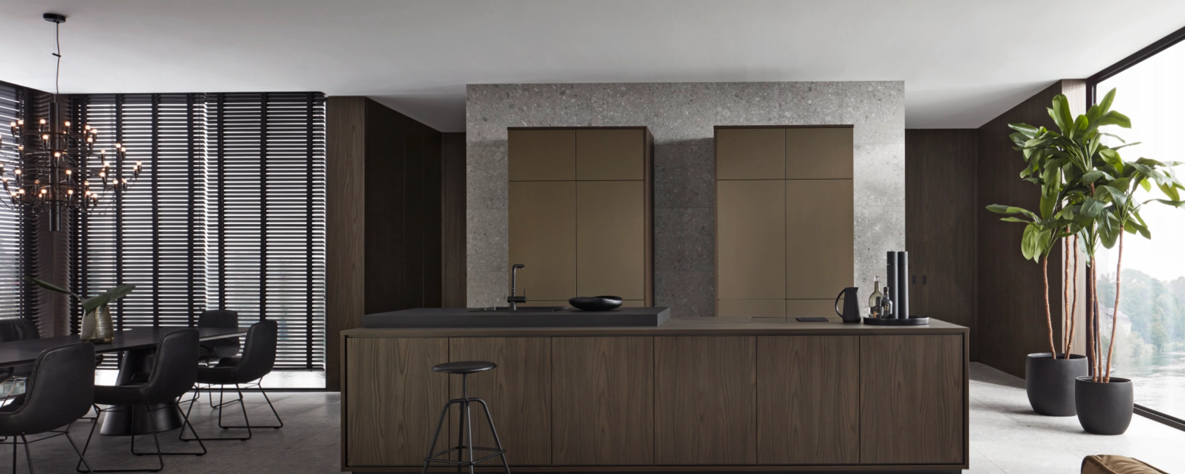 Cuisine moderne avec îlot, table à manger et plantes, aménagée avec style par Nolte Kitchen.