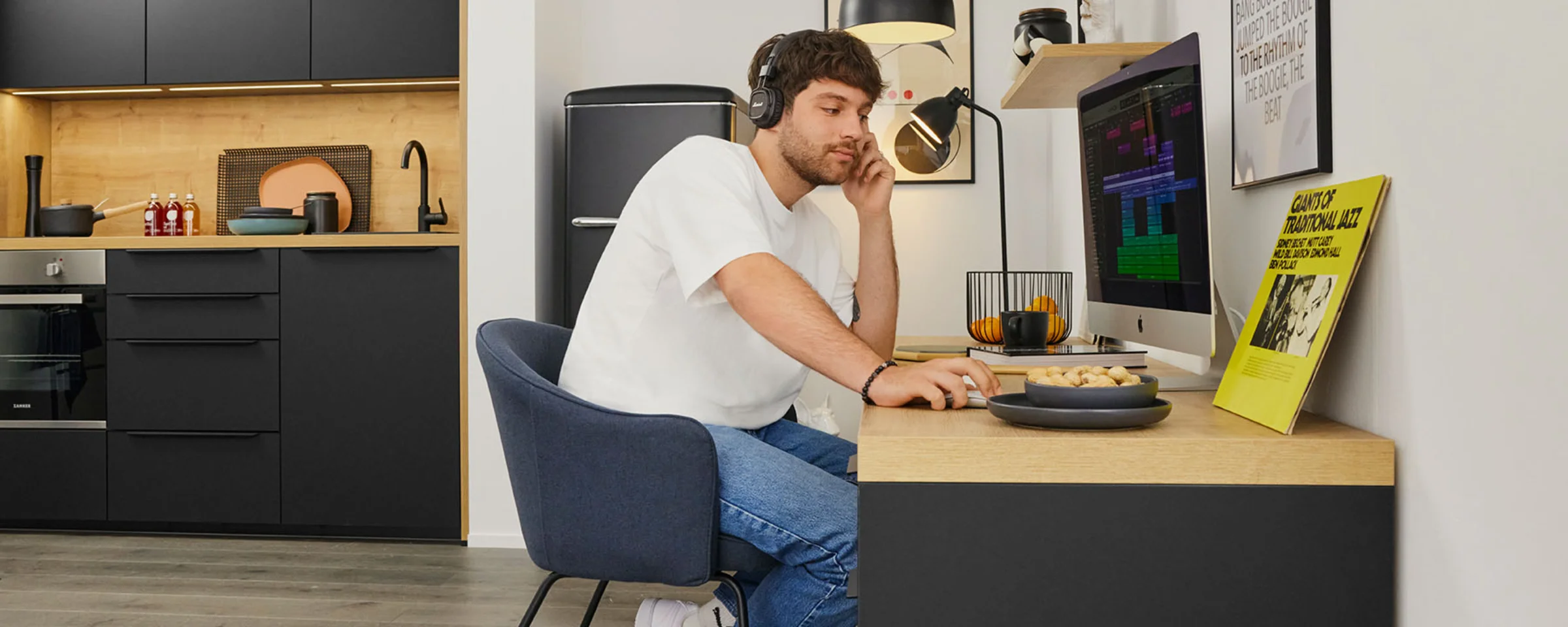 Ein Mann arbeitet in einer modernen Küche von Nolte Küchen am Schreibtisch mit einem Computer.