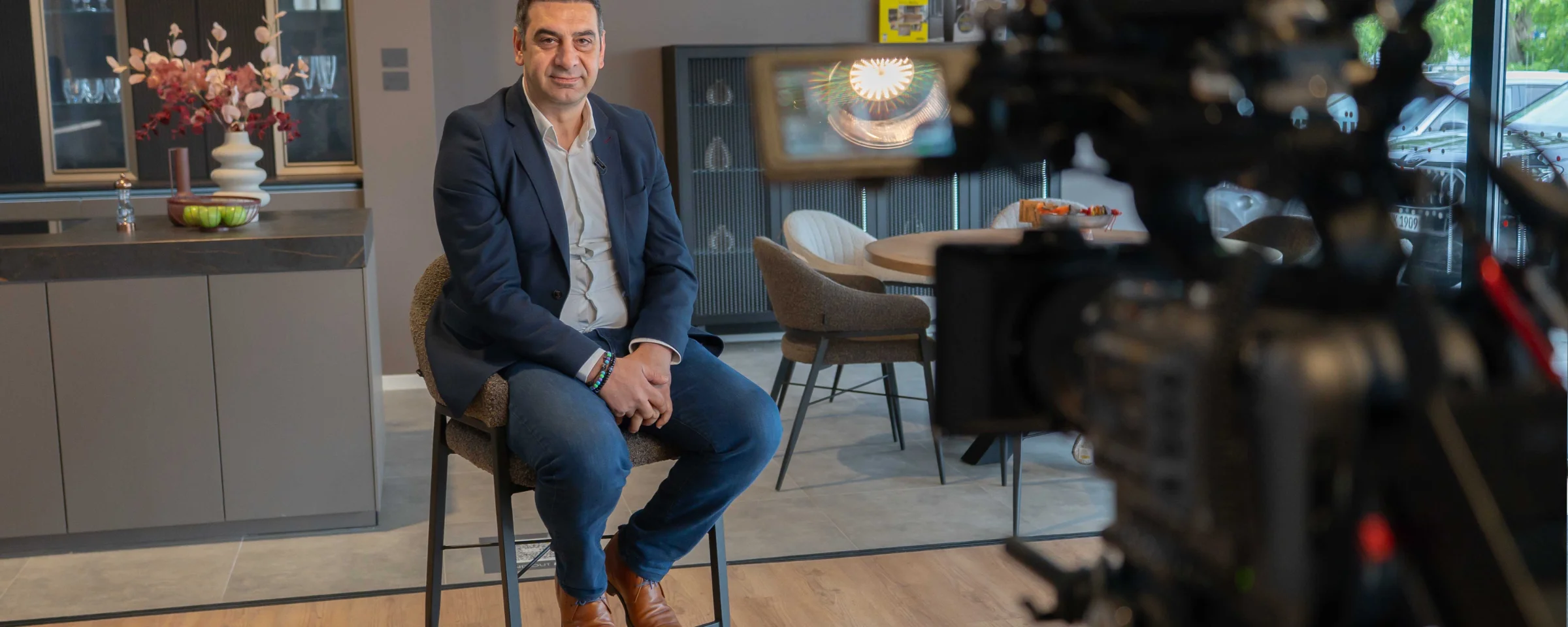 Un homme est assis sur un tabouret dans une cuisine moderne conçue par NolteNeo.