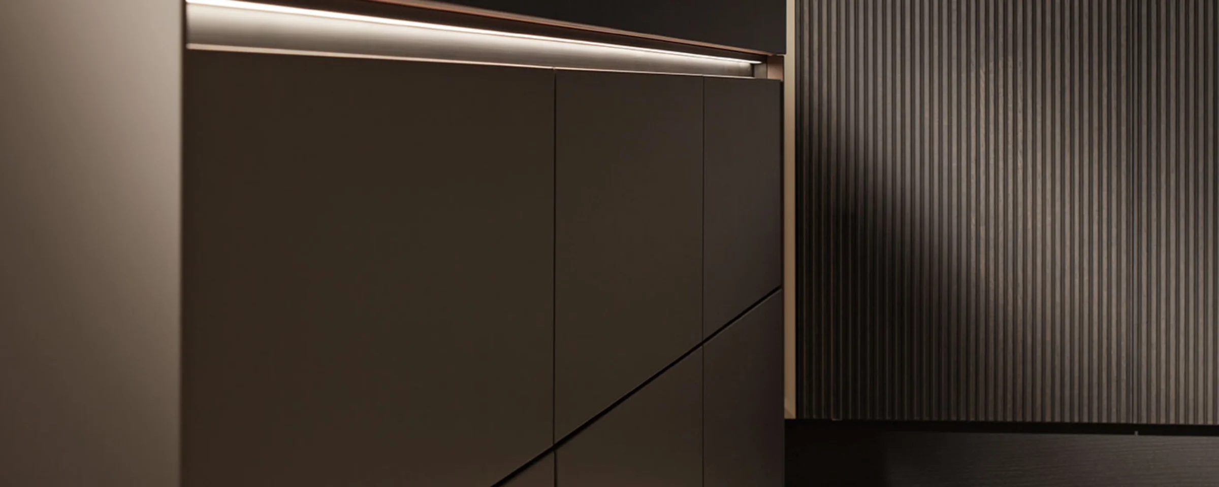 Eine moderne Küche mit eleganten, dunklen Schränken und Beleuchtung von Nolte Küchen.