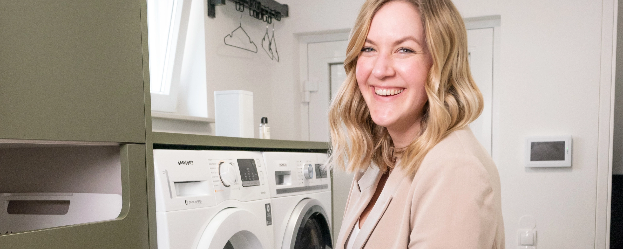 Une femme dans une buanderie moderne avec lave-linge et sèche-linge de Nolte Utility Rooms.