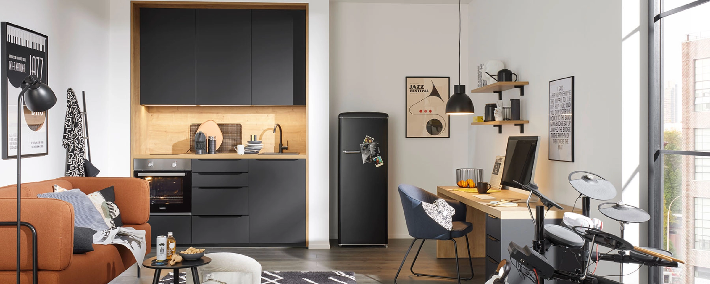 Cuisine moderne avec armoires noires et espace de vie cosy par Nolte Kitchen.