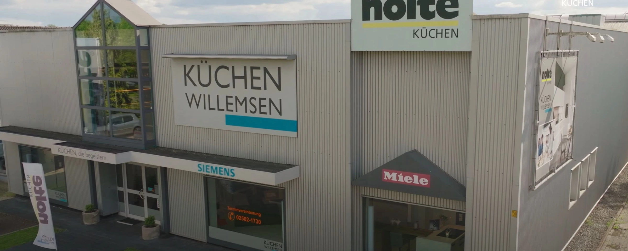 Un edificio con letreros de Küchen Willemsen, Siemens y Miele, al fondo Nolte Cocina.