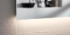 Een verlichte badkamerspiegel met plank in Nolte SPA design.