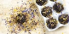 Une boîte à œufs avec des muffins au chocolat décorés de fleurs séchées sur une planche en bois.