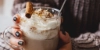 Eine Person hält eine Tasse heiße Schokolade mit Sahne und Zimtstange.