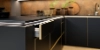 Cuisine moderne avec armoires noires et accents dorés, conçue par Nolte Kitchen.
