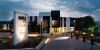Un bâtiment moderne au crépuscule avec un panneau Nolte Kitchen éclairé au premier plan.