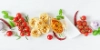 Deux personnes préparent ensemble un repas. Sur un plan de travail de cuisine, des légumes sont coupés et une salade est mélangée.
