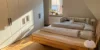 Ein Schlafzimmer mit einem Doppelbett und Kleiderschrank, beleuchtet von Sonnenlicht, gehört zu Nolte Living.