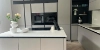 Cuisine moderne avec armoires grises et îlot, élégamment aménagée par Nolte Kitchen.