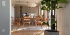 A dining area with a wooden table and chairs next to a large houseplant, bathed in natural light, Nolte Living.