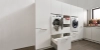 Une buanderie moderne avec lave-linge et sèche-linge intégrés dans des armoires blanches Nolte.