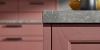 Une cuisine élégante avec des armoires roses et un plan de travail gris, présentée par Nolte Kitchen.