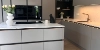 Cuisine moderne avec armoires grises et îlot central. Nolte Kitchen.