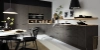 Cuisine moderne avec armoires sombres et éclairage élégant, conçue par Nolte Kitchen.