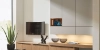 Een modern ingerichte woonkamer met stijlvolle kasten en tv, versierd met planten en sculpturen, Nolte Living.