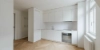 Eine moderne, minimalistische Küche mit weißen Schränken und Holzfußboden von Nolte Küchen.