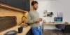 A man stands in a modern kitchen with wood accents and black decor, Nolte Kitchen.