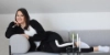 Une femme se détend sur un canapé gris, faisant partie de la collection Nolte Living.