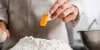 Une personne sépare un jaune d'œuf au-dessus d'un tas de farine dans une cuisine moderne de Nolte Kitchen.