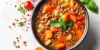 A bowl of lentil soup garnished with fresh herbs, surrounded by tomatoes and spices.