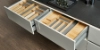 Cuisine moderne avec tiroirs ouverts et compartiments en bois, équipée par Nolte Kitchen.