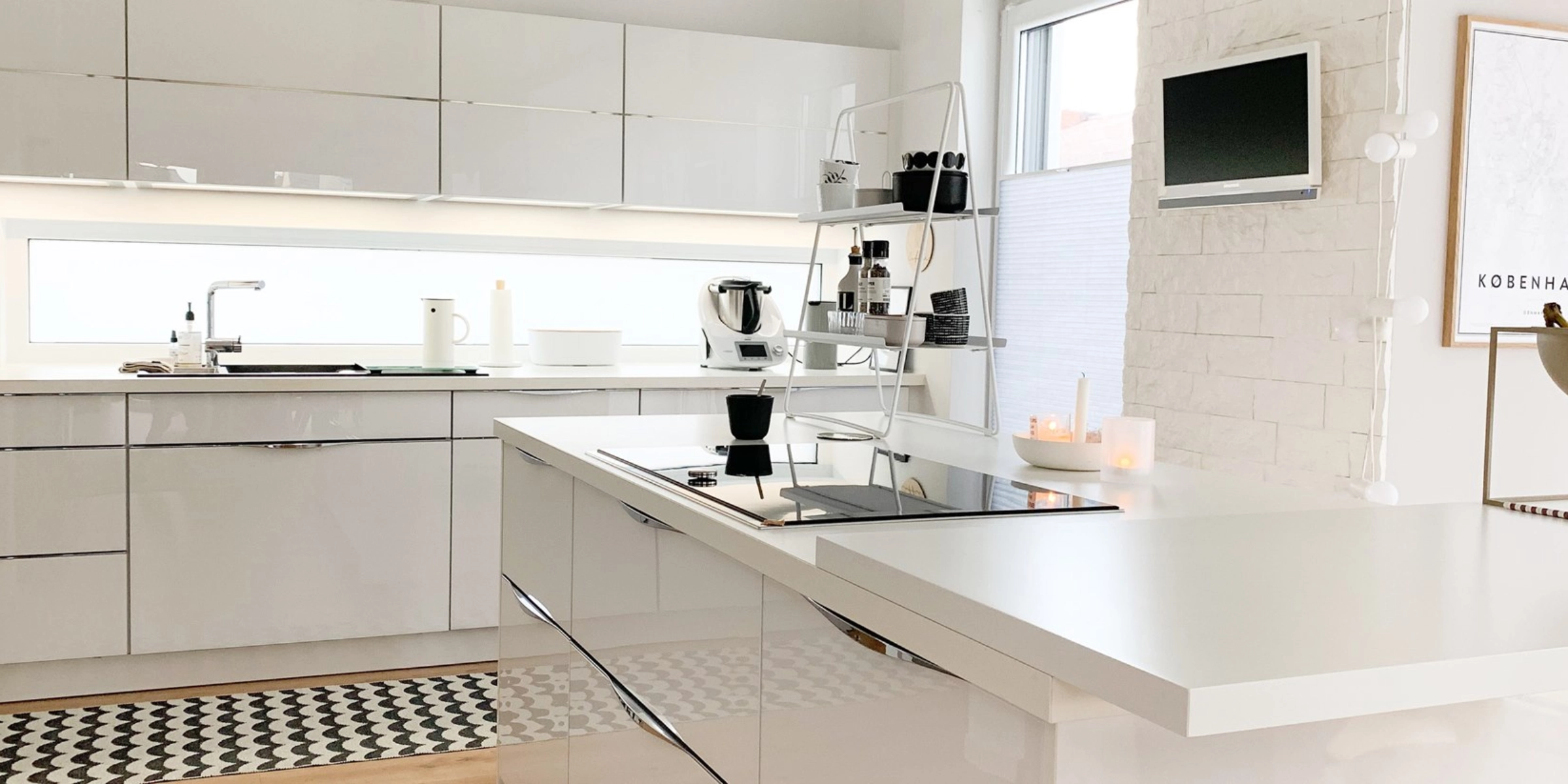Une cuisine moderne avec façades blanches brillantes et îlot de cuisson, Nolte Kitchen.