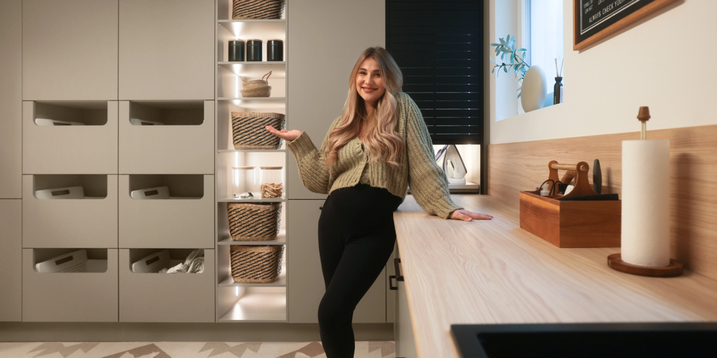Een vrouw staat glimlachend in een moderne bijkeuken van Nolte Utility Rooms.