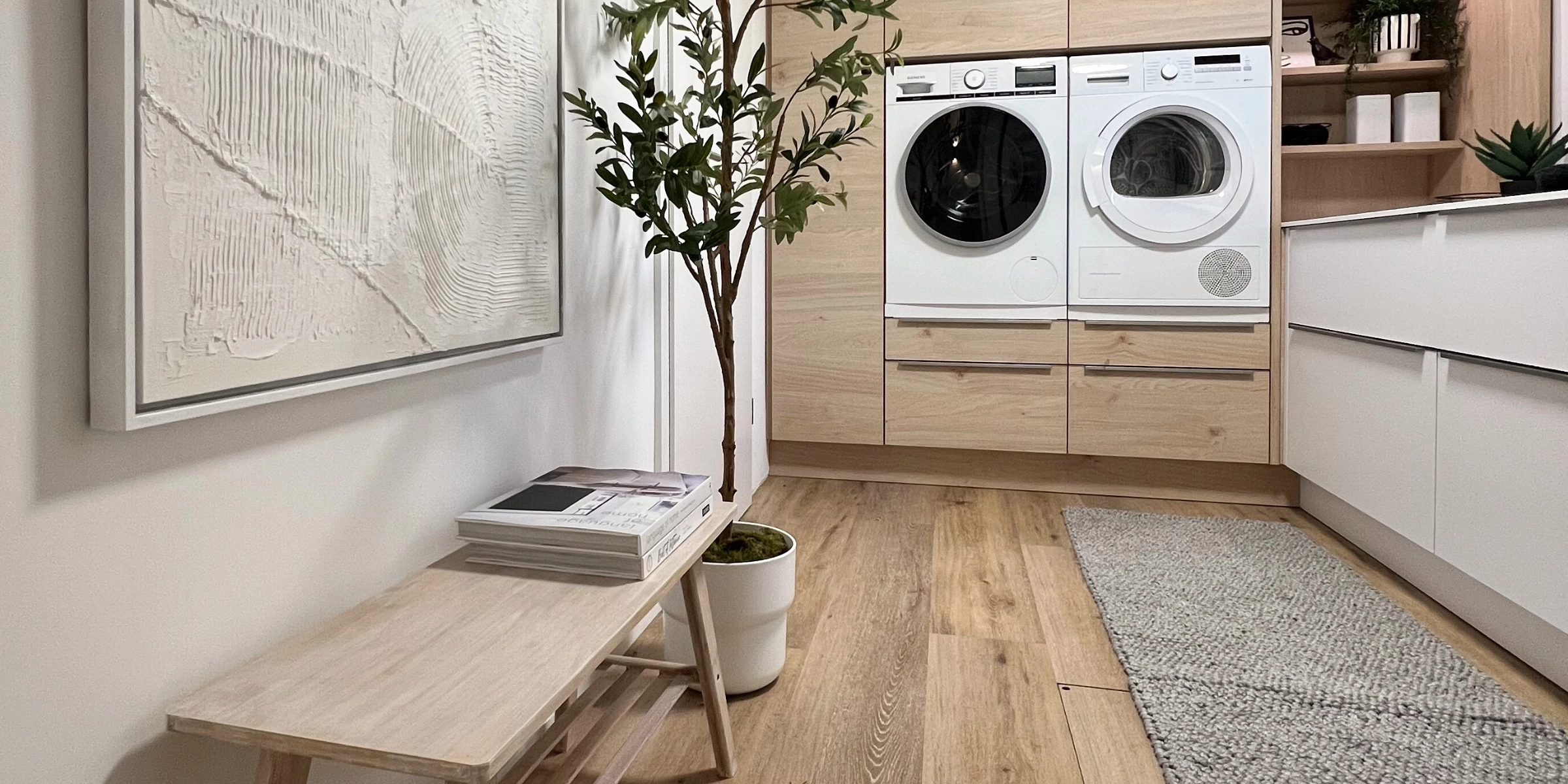 Un cuarto de lavado con lavadora, secadora y plantas decorativas. Cuartos de lavado Nolte.