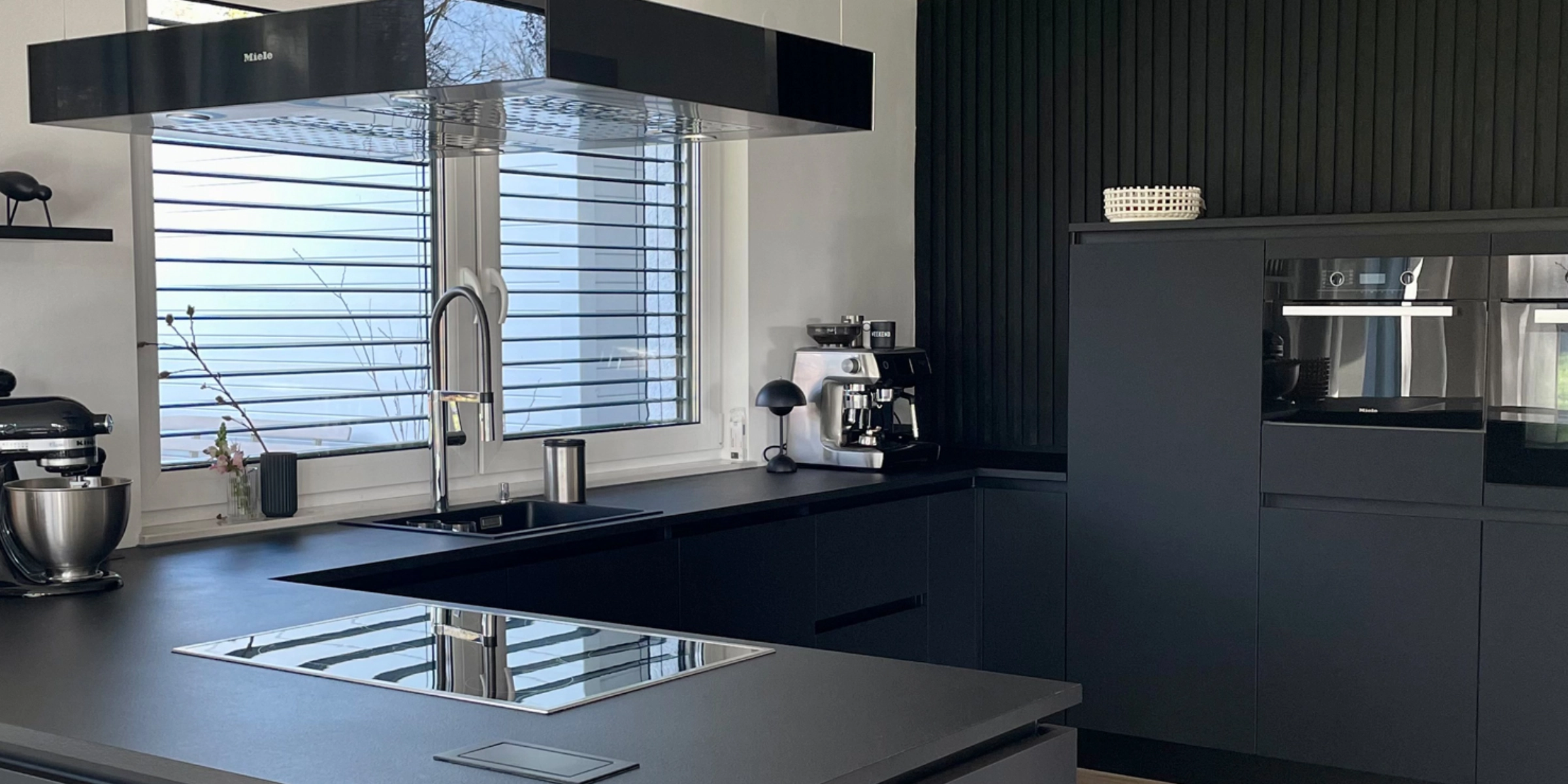 Eine moderne Küchenzeile in dunklem Design mit Geräten und Fenster. Nolte Küchen.