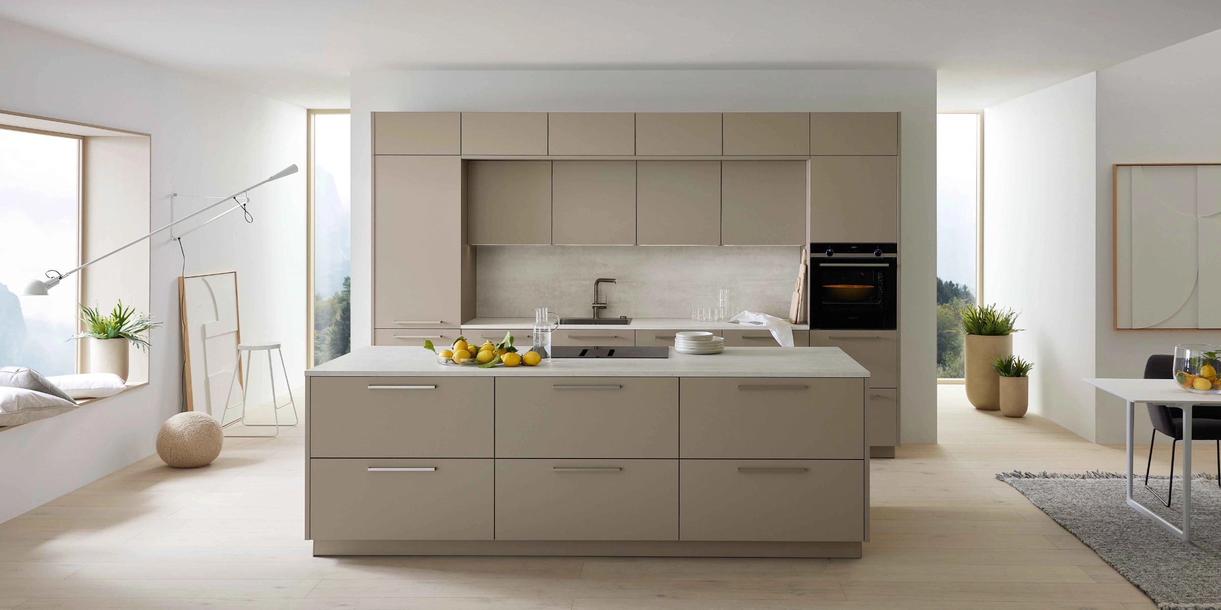 Cuisine moderne avec îlot, armoires claires et grandes fenêtres, conçue par Nolte Kitchen.