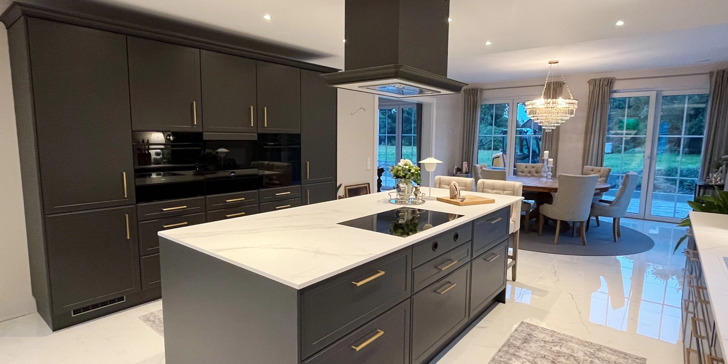 Cuisine moderne avec armoires sombres et grand îlot, salle à manger en arrière-plan, par Nolte Kitchen.