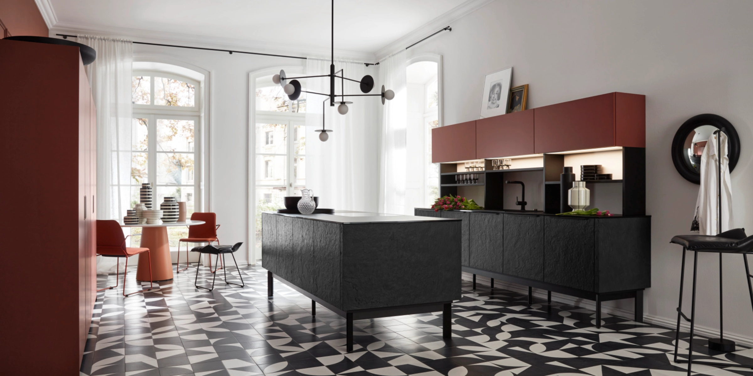 A modern kitchen with a geometric tile floor and a black island by Nolte Kitchen.