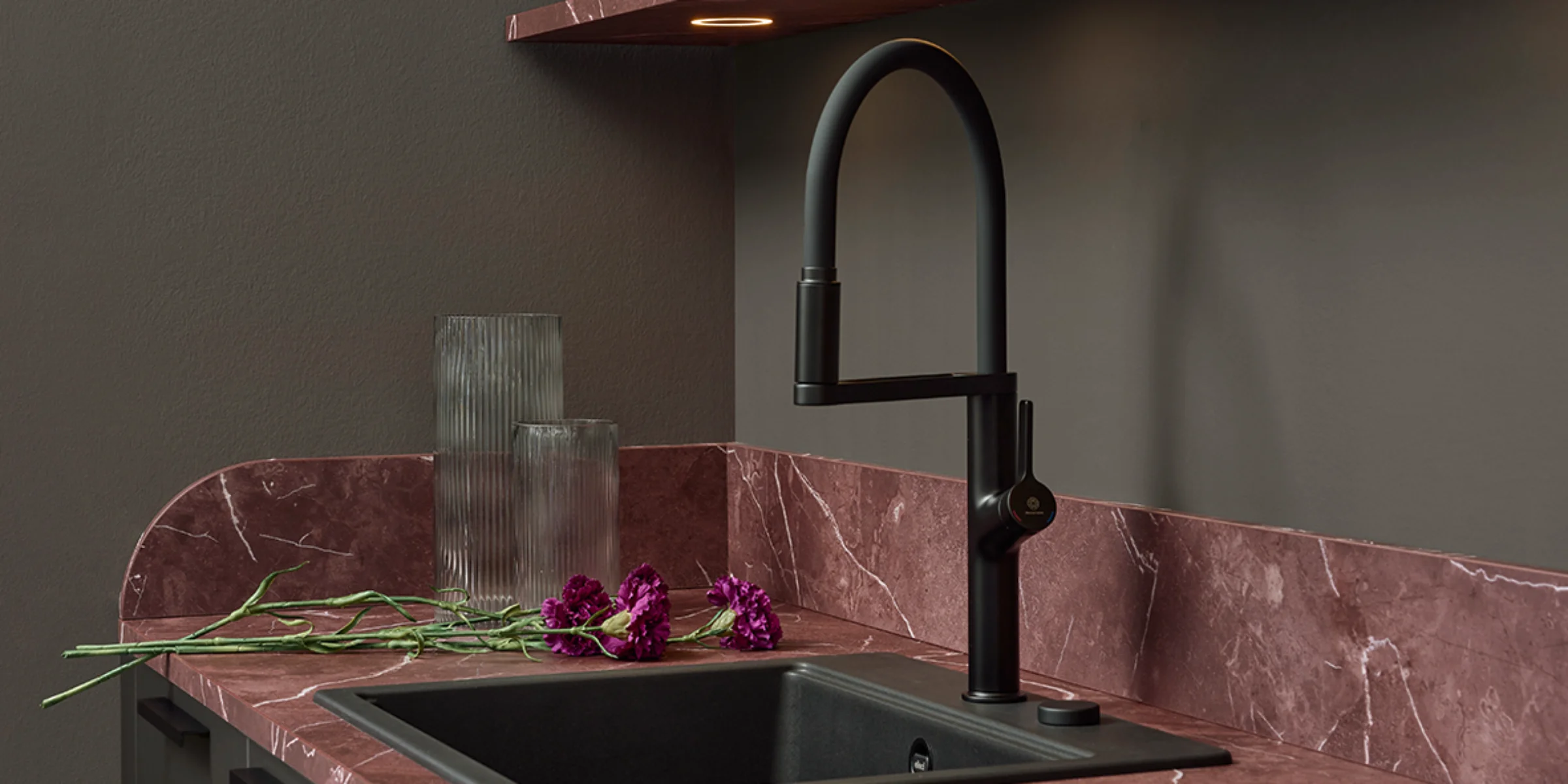 Un fregadero de cocina moderno con grifo y área de almacenamiento, rodeado de madera y piedra. Nolte Cocina.