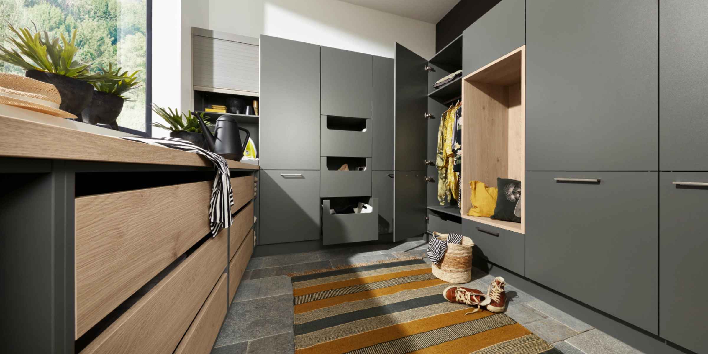 Une buanderie avec des armoires et étagères grises, conçue par Nolte Utility Rooms.