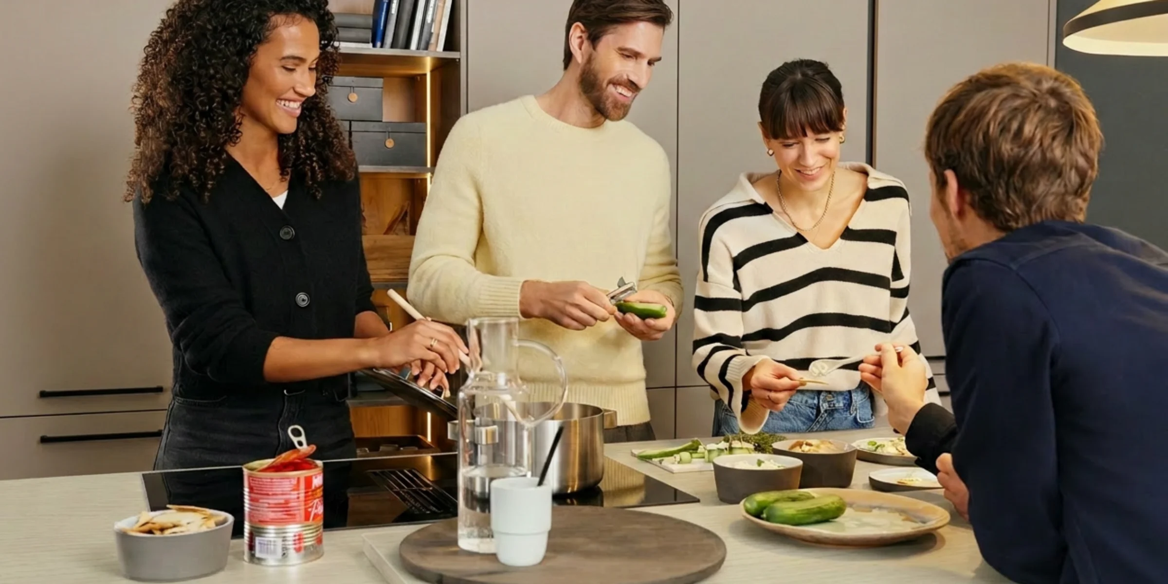 A modern Nolte kitchen-diner with a cooking island, featuring snacks and drinks, atmospherically lit, and set up for a kitchen party with guests.