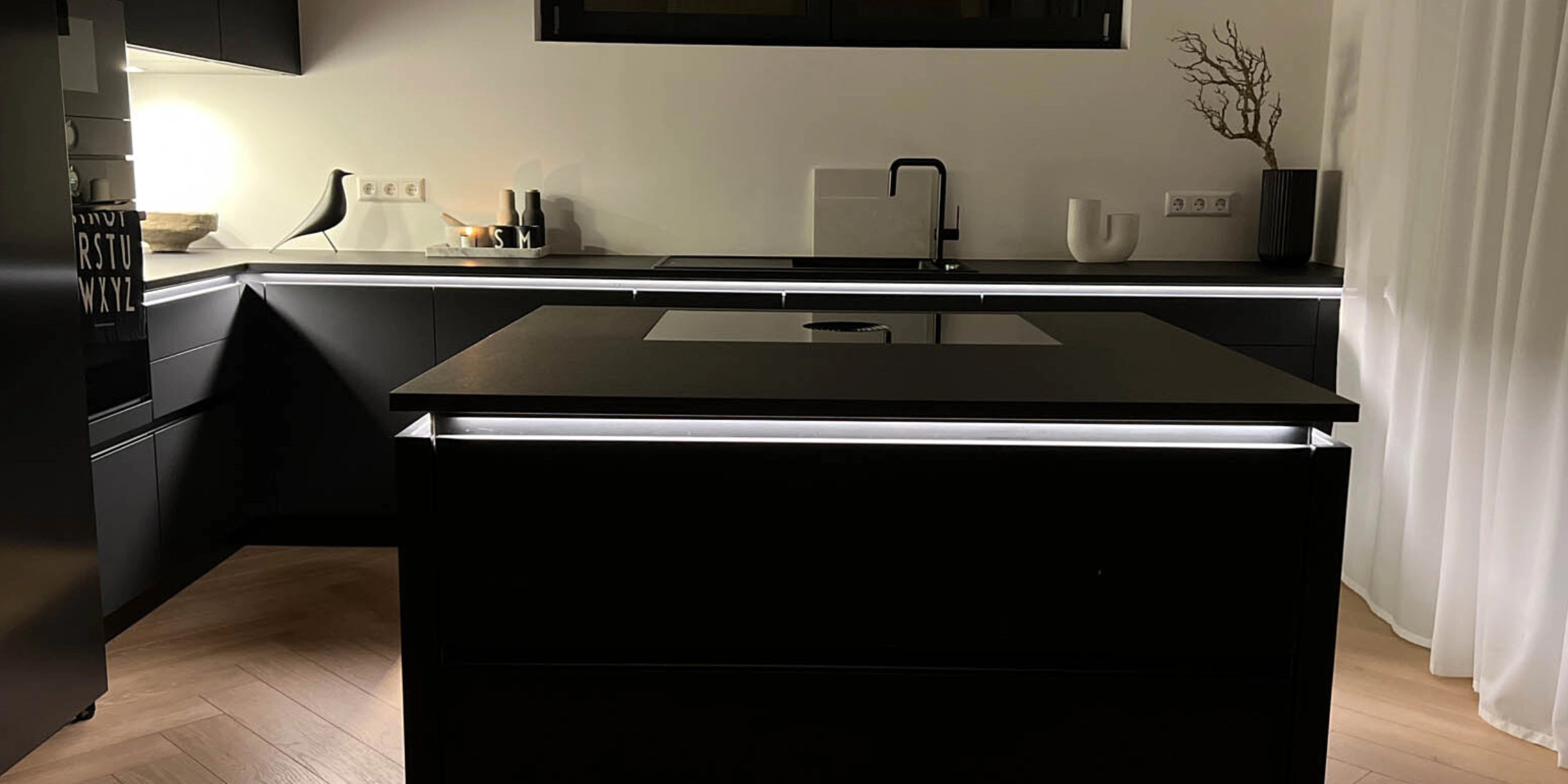 Cucina moderna e scura con isola e illuminazione, progettata da Nolte Kitchen.