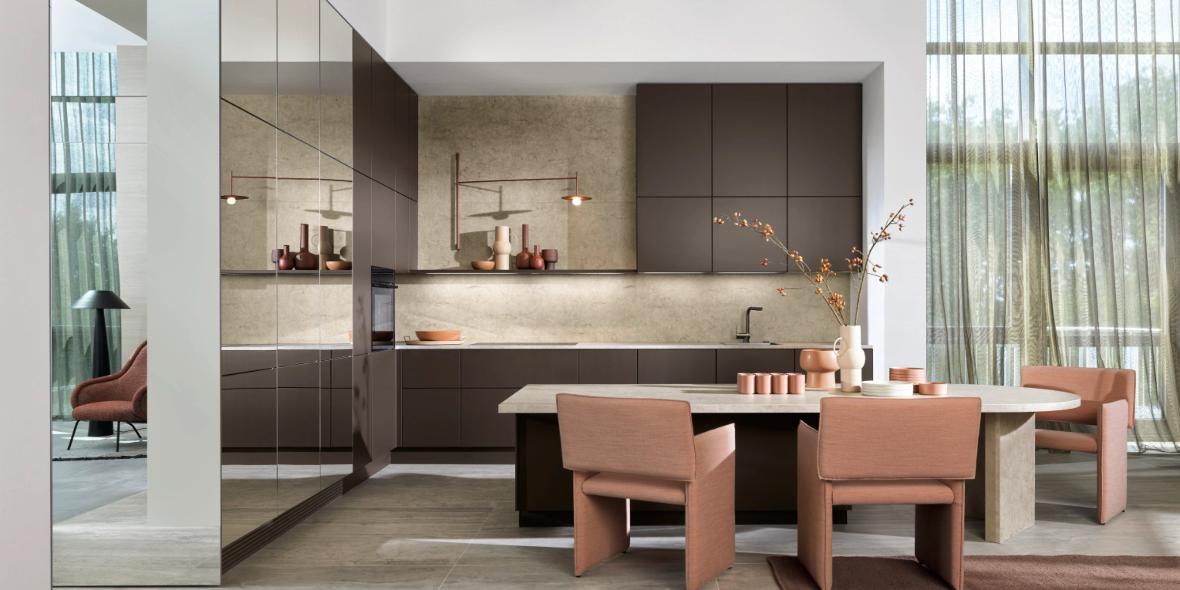 Moderne Nolteneo keuken met neoMIRROR-front in spiegeloptiek en Soft Lack-front in Sepiabruin. Greeploze kasten, steenkleurig werkblad en ronde eettafel met gestoffeerde stoelen in een stijlvol, lichtovergoten ambiance.