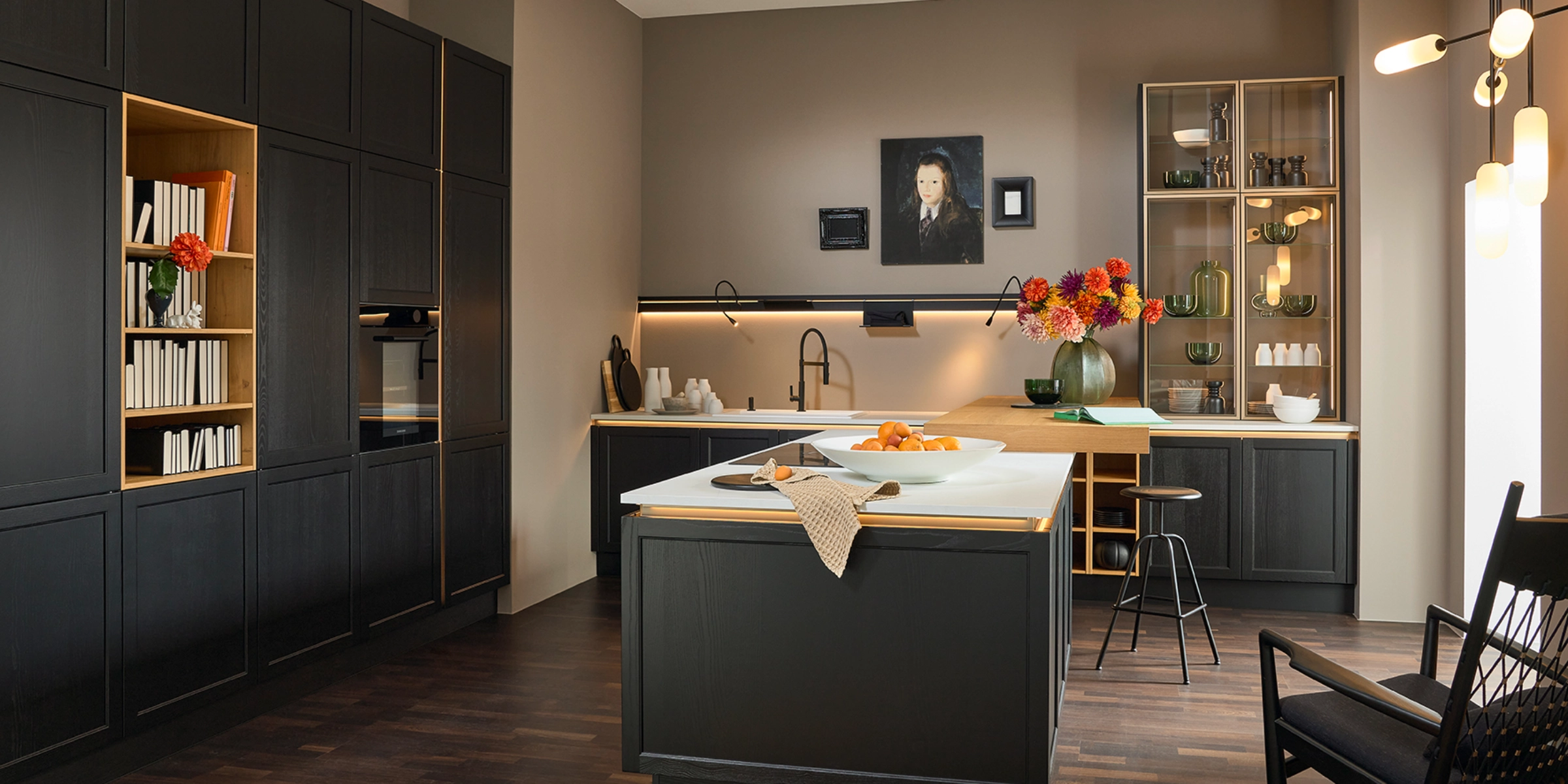 A modern kitchen with dark cabinets and a light countertop, designed by Nolte Kitchen.
